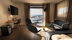 Una moderna camera d'hotel con vista sull'oceano, una scrivania, una sedia, un divano e una televisione.