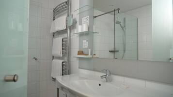 Een badkamer met een witte wastafel, glazen schappen, een douchecabine van glas en een handdoekhouder.