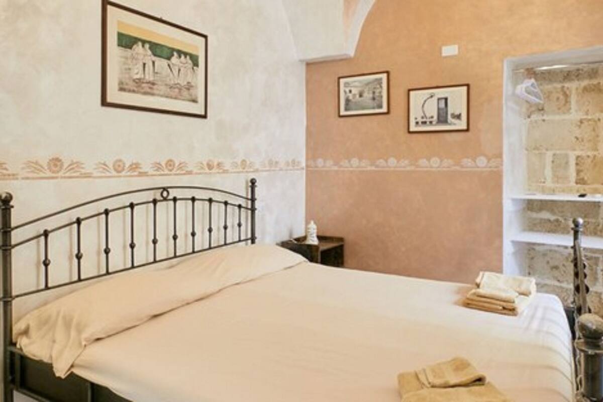 A bedroom with a bed, a nightstand, and a stone wall.