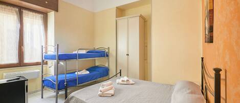 A bedroom with bunk beds, a wardrobe, and a desk.