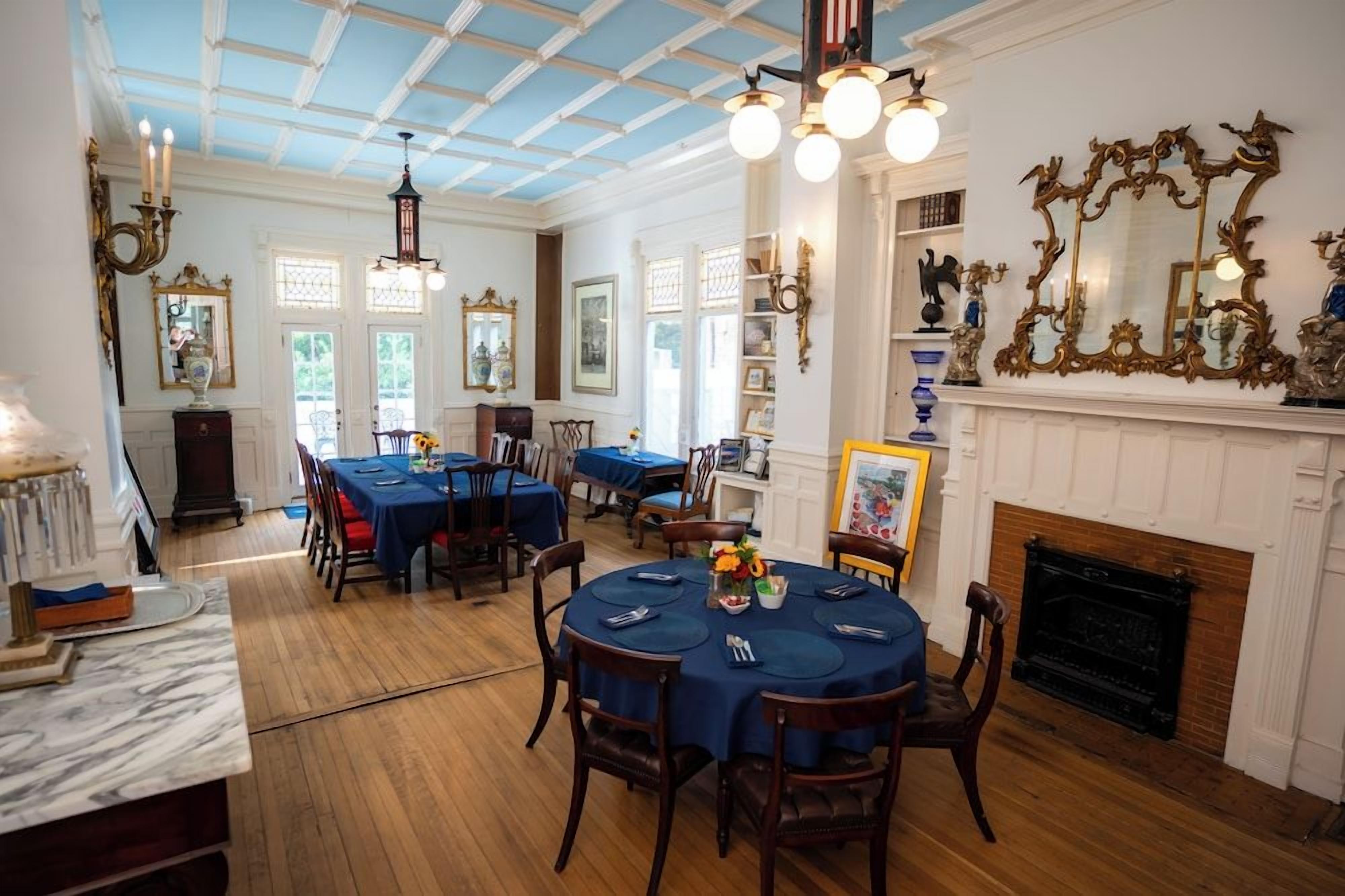 A dining room with round tables, chairs, and a fireplace.