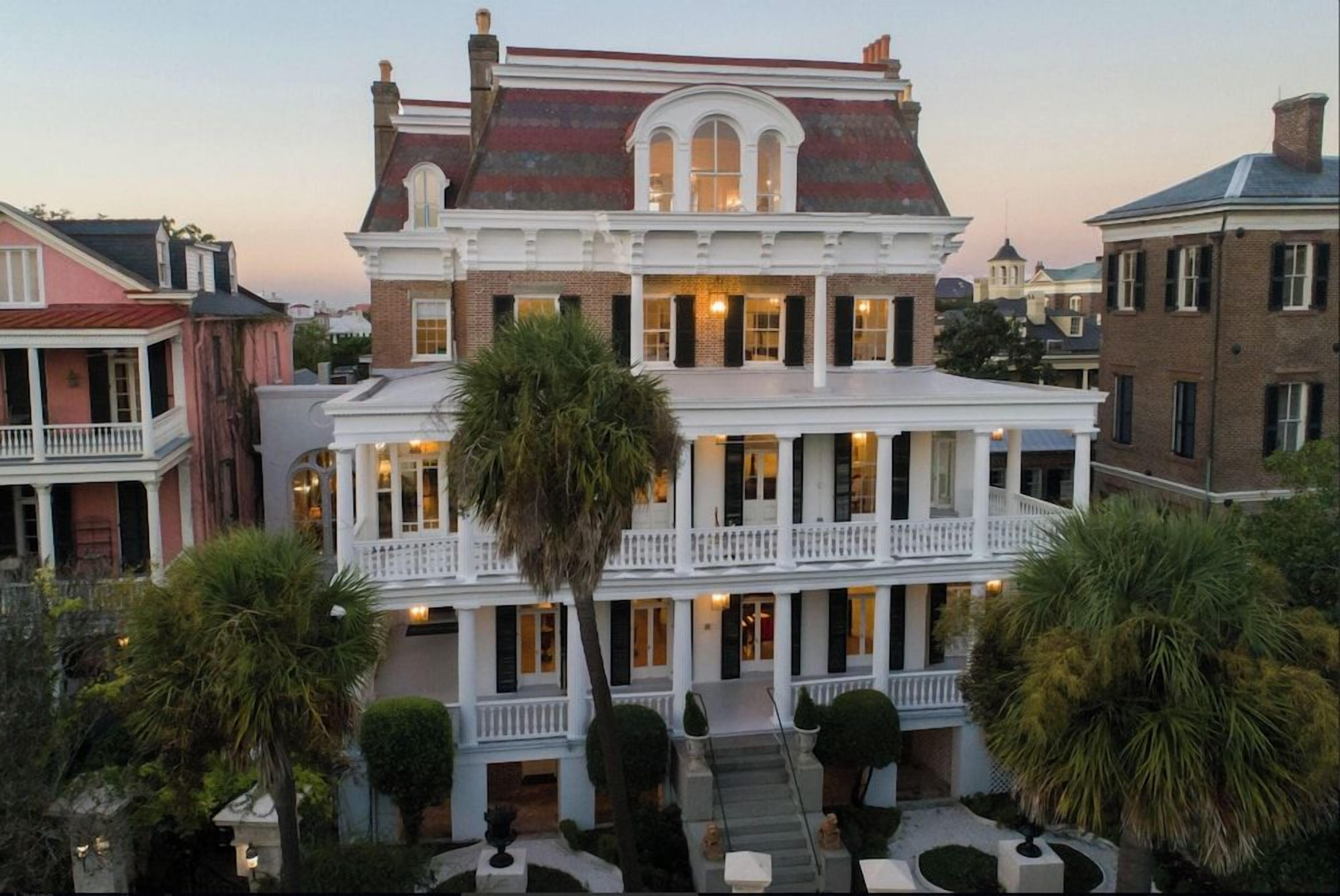 A two-story building with a balcony, a covered front porch, and a symmetrical facade.