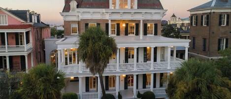 A two-story building with a balcony, a covered front porch, and a symmetrical facade.