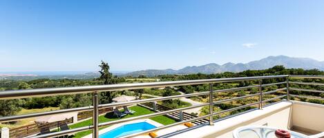 Un balcón con piscina, mobiliario exterior y vistas a las montañas.