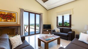 A modern living room with a fireplace, a television, and a sofa. - Anatoli Villa, a Retreat with Private Pool & BBQ (Rethymno)