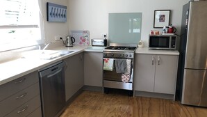 A modern kitchen with stainless steel appliances, a dishwasher, a stove, and a microwave. - Walk to the wharf and village (Mapua (Ruby Bay))