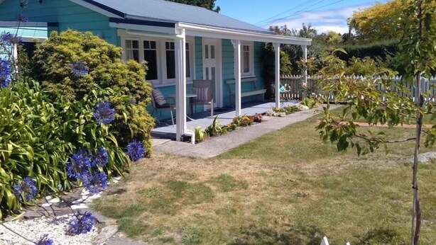 A house with a covered porch, a lawn, and a white picket fence. - Walk to the wharf and village (Mapua (Ruby Bay))