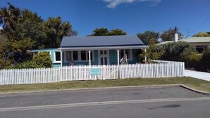 A two-story house with a white picket fence, a blue roof, and a signboard. - Walk to the wharf and village (Mapua (Ruby Bay))