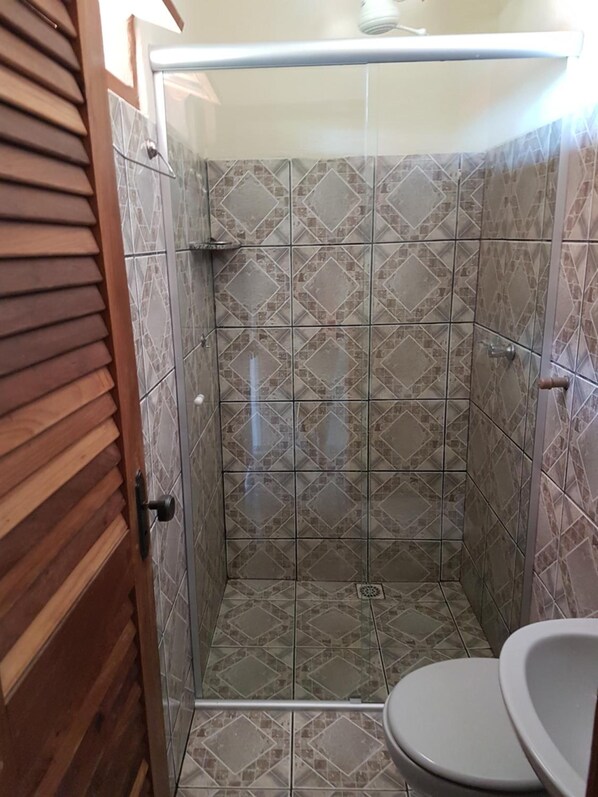 A shower stall with a tiled wall and a toilet. - Pousada Betta (Pirenópolis)