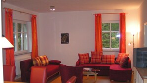 Ein Wohnzimmer mit roten Sofas, einem Couchtisch und einem Fernseher.