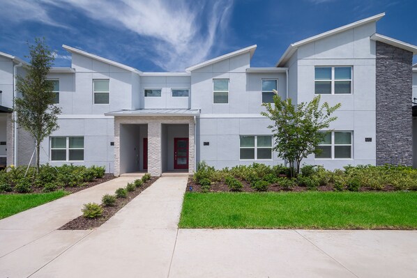 A modern two-story building with a symmetrical facade, a central entrance, and a landscaped front yard. - RG670 Champions Gate Condo 4 Bed 3 Bath Private Pool & Free Waterpark (Davenport)