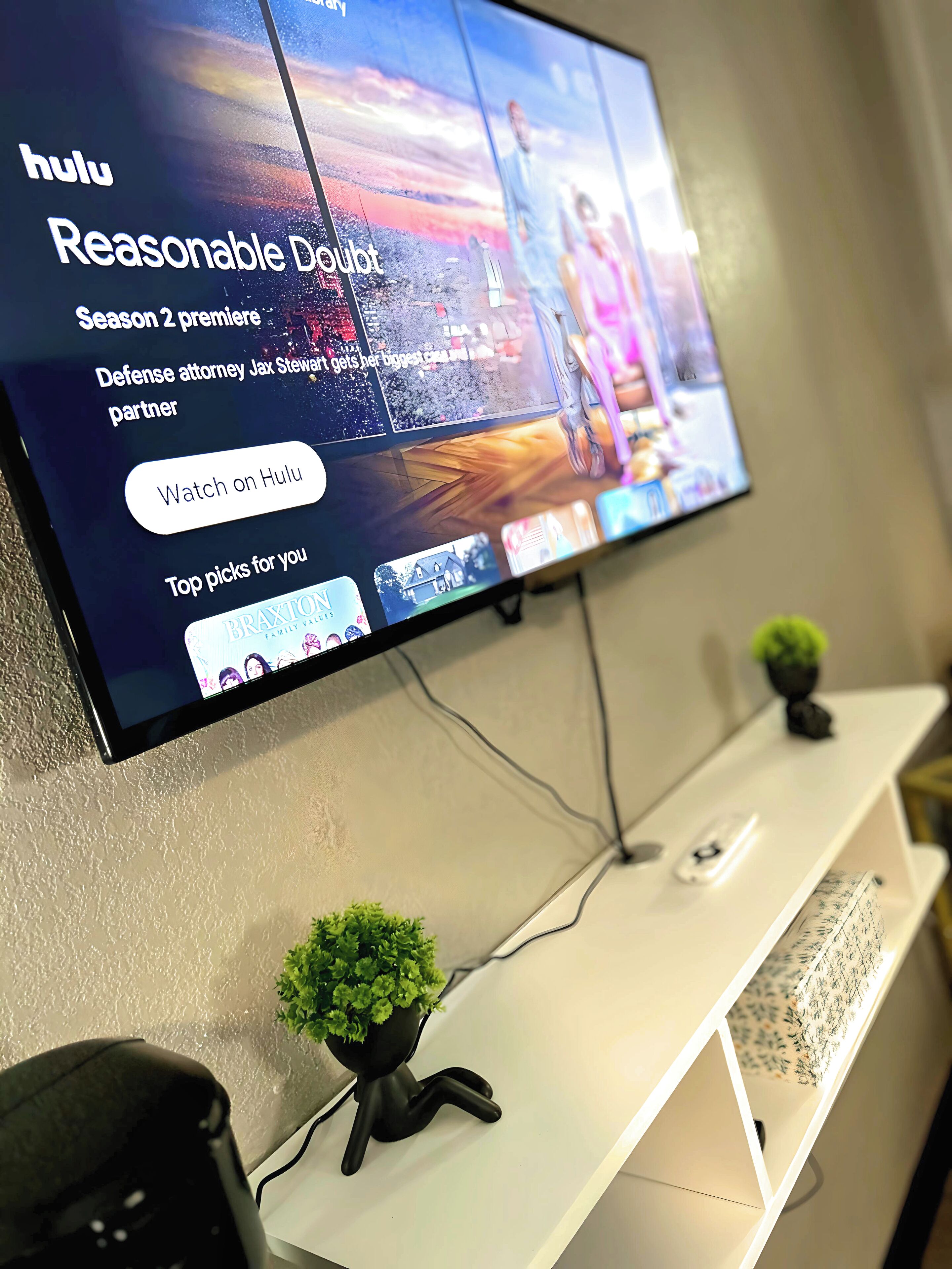 Un téléviseur à écran plat fixé au mur, diffusant une émission de Hulu.