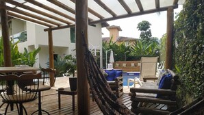 An outdoor patio with a hammock, wooden deck, and a pool area. - Mares de Camburizinho (São Sebastião)