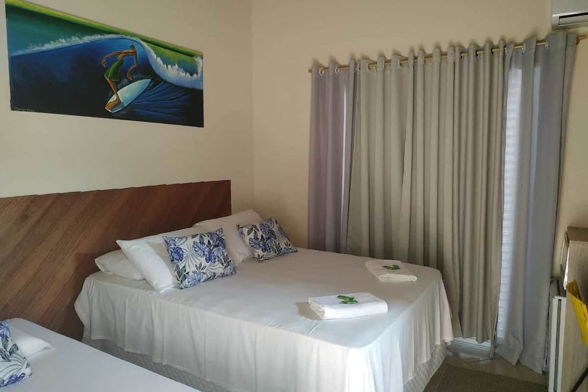 Une chambre d’hôtel avec un lit, deux oreillers, une couverture et un tableau au mur.