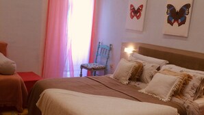 Ein Schlafzimmer mit einem Bett, einem Sessel und zwei Schmetterlingsbildern an der Wand.
