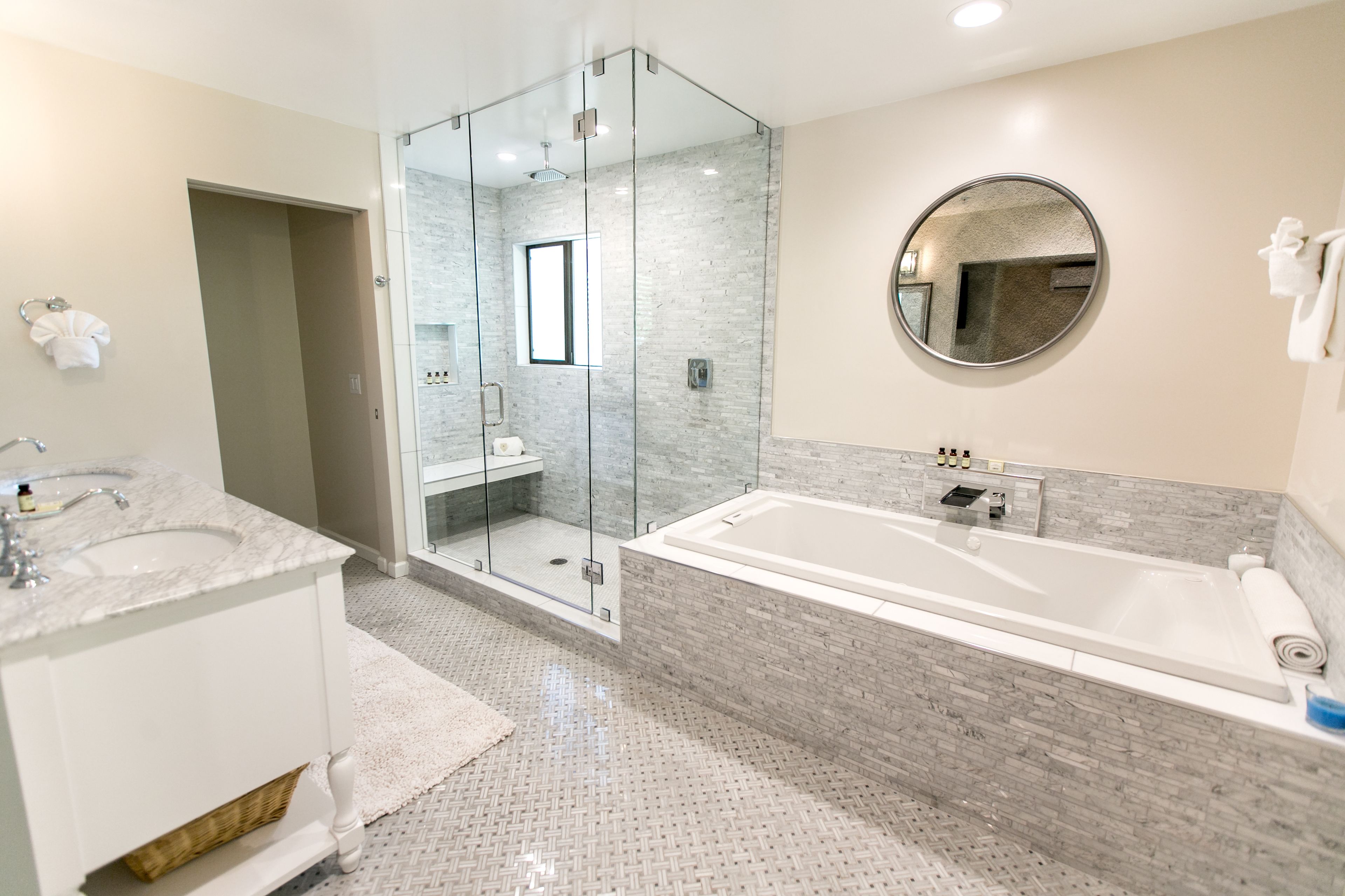 A modern bathroom with a glass-enclosed shower, a large bathtub, and a vanity with a sink and mirror.