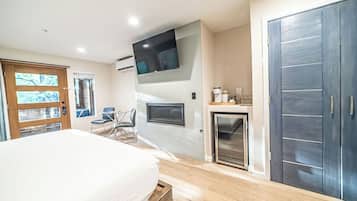 A bedroom with a bed, a TV mounted on the wall, a fireplace, and a wardrobe.