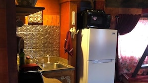 Una cocina compacta con un refrigerador, un microondas y un lavamanos.