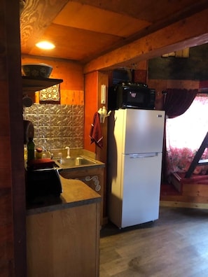 Una cucina compatta con frigorifero, forno a microonde e lavandino.