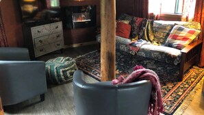 Una sala de estar acogedora con un sofá, dos sillones, una mesa de centro de madera, una chimenea y un espejo grande.