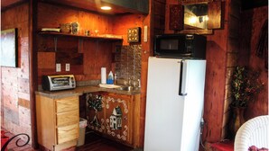 Una cocina compacta con armarios de madera, un refrigerador blanco, un microondas y un tostador.