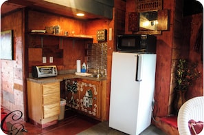 Una cucina compatta con mobili in legno, un frigorifero bianco, un forno a microonde e un tostapane.