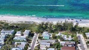 Vista aérea de una zona residencial costera con casas, una playa y una vista despejada del océano.