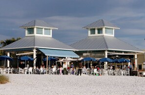 Un restaurante frente al mar con mesas al aire libre y un patio cubierto.