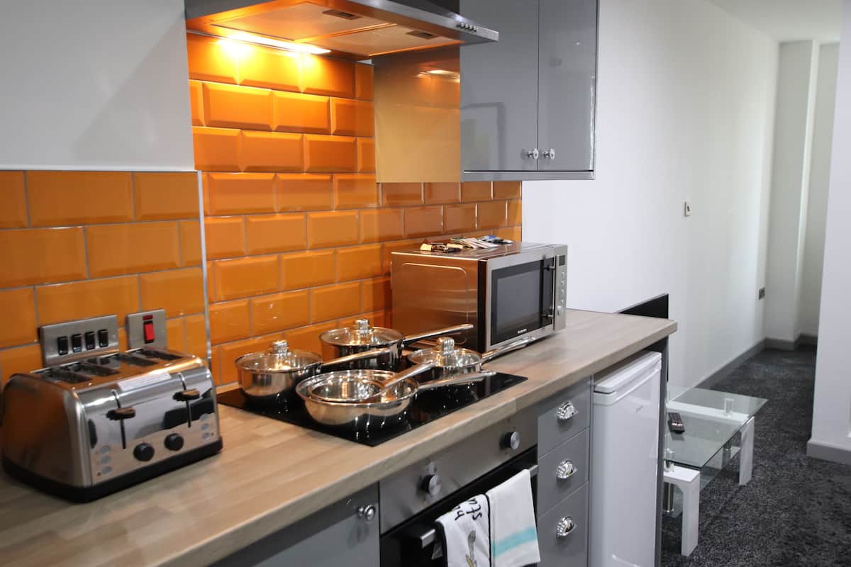 A compact kitchen with a toaster, microwave, stove, and a small refrigerator.