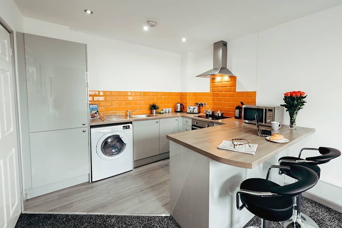 A modern kitchen with a washing machine, a microwave, and a sink.