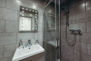 A modern bathroom with a glass-enclosed shower, a vanity with a mirror, and a sink. - Halifax House Apartments (Halifax)