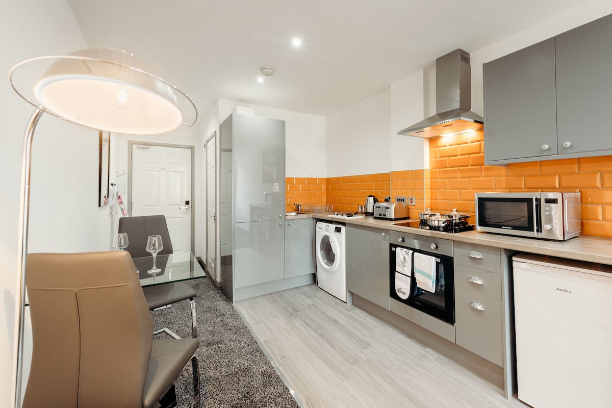 A modern kitchen with a washing machine, microwave, and oven.