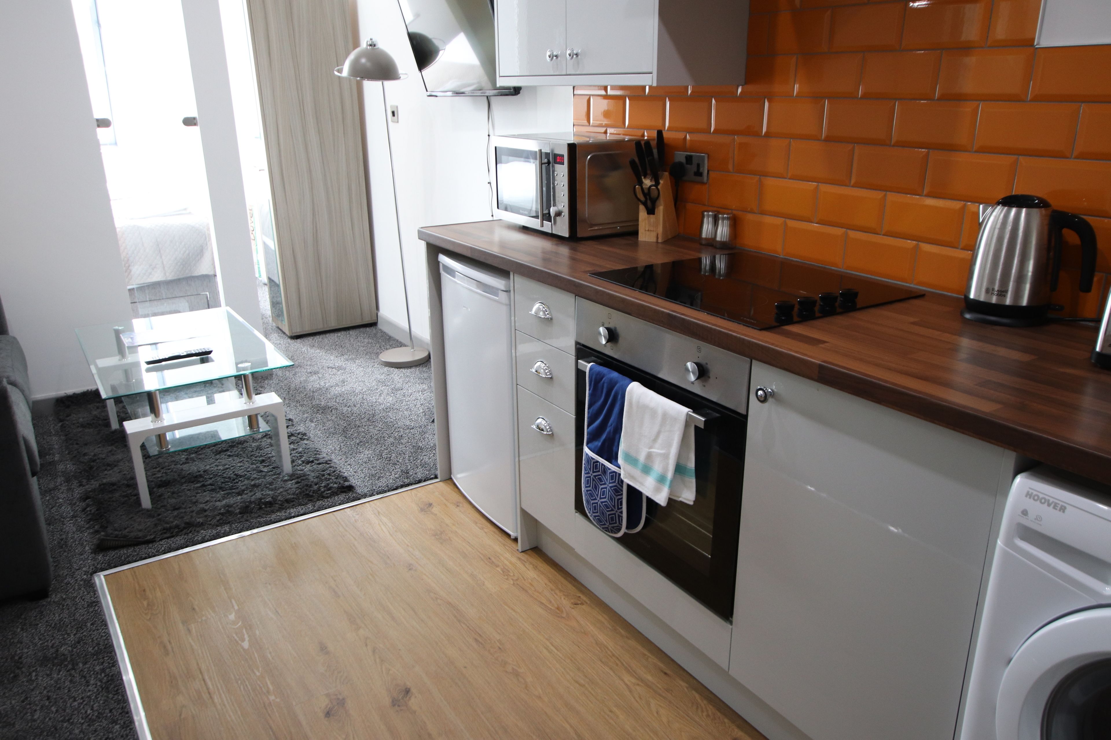 A compact kitchen with a microwave, oven, and dishwasher, a small table, and a washing machine.