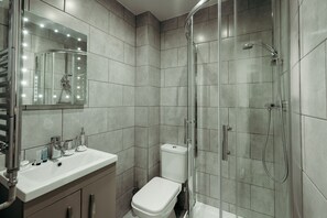 A bathroom with a glass-enclosed shower, a vanity with a mirror, and a toilet. - Halifax House Apartments (Halifax)