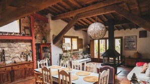 A rustic dining area with a stone wall, wooden furniture, and a hanging light fixture.