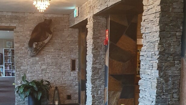 A spacious lobby with stone walls, a chandelier, and potted plants. - Rødungstøl Høyfjellshotell (Al)
