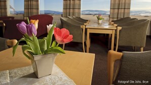 A dining area with a table, chairs, and a potted plant with tulips. - Rødungstøl Høyfjellshotell (Al)