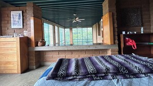 Una habitación con cama, escritorio, ventana con vista y ventilador de techo.