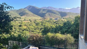 Un patio con mesa y sillas, con vistas a un paisaje montañoso.