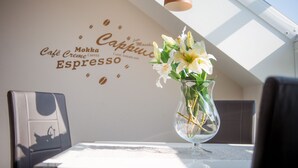Un mur décoré avec des motifs évoquant le café, un vase rempli de fleurs et une table avec une chaise.