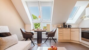 Un appartement moderne doté d’une cuisine de style industriel, d’un coin repas avec une table ronde et d’un espace salon confortable avec un canapé et des fauteuils.