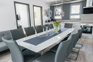 Un espace repas moderne avec une longue table, des chaises grises et un vase rempli de fleurs.