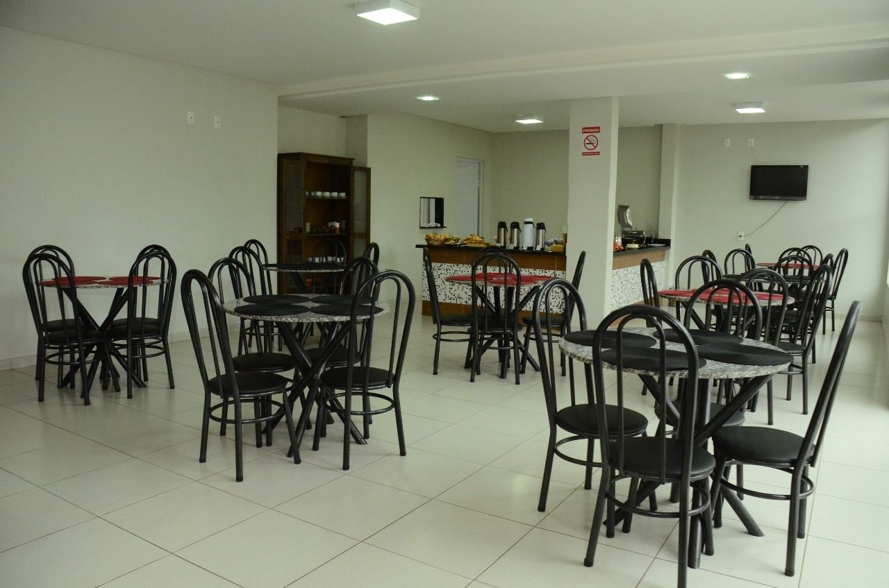 A dining area with multiple tables and chairs, a counter with a coffee machine, and a television mounted on the wall.
