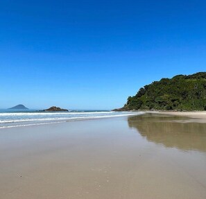 A beach with clear blue skies, calm waters, and a forested hill. - House - Cond Closed - Juquehy - 6 people (São Sebastião)