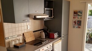 Een kleine keuken met grijze kastjes, een magnetron, een broodrooster en een vaatwasser.