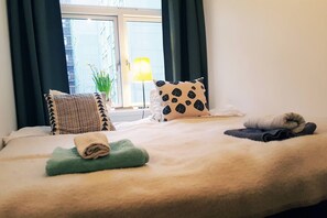 Comfortable bed with a beige duvet and two pillows, featuring a geometric and checkered design.
