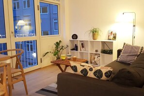 Relax in this inviting living room with a sofa, dining table, and shelving unit, offering a view of the exterior.