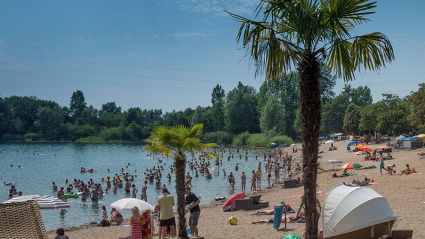 A beach with people swimming and sunbathing, tents, and umbrellas. - "Bathroom apartment" for bathing beauties with Roman bath tub / 1-2P / Parking free! (Bensheim)