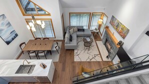 Un espace de vie moderne comprenant un coin repas, un canapé, une cheminée et un escalier.