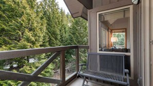 Un balcon avec une balustrade en bois, un banc et une fenêtre avec une lampe.